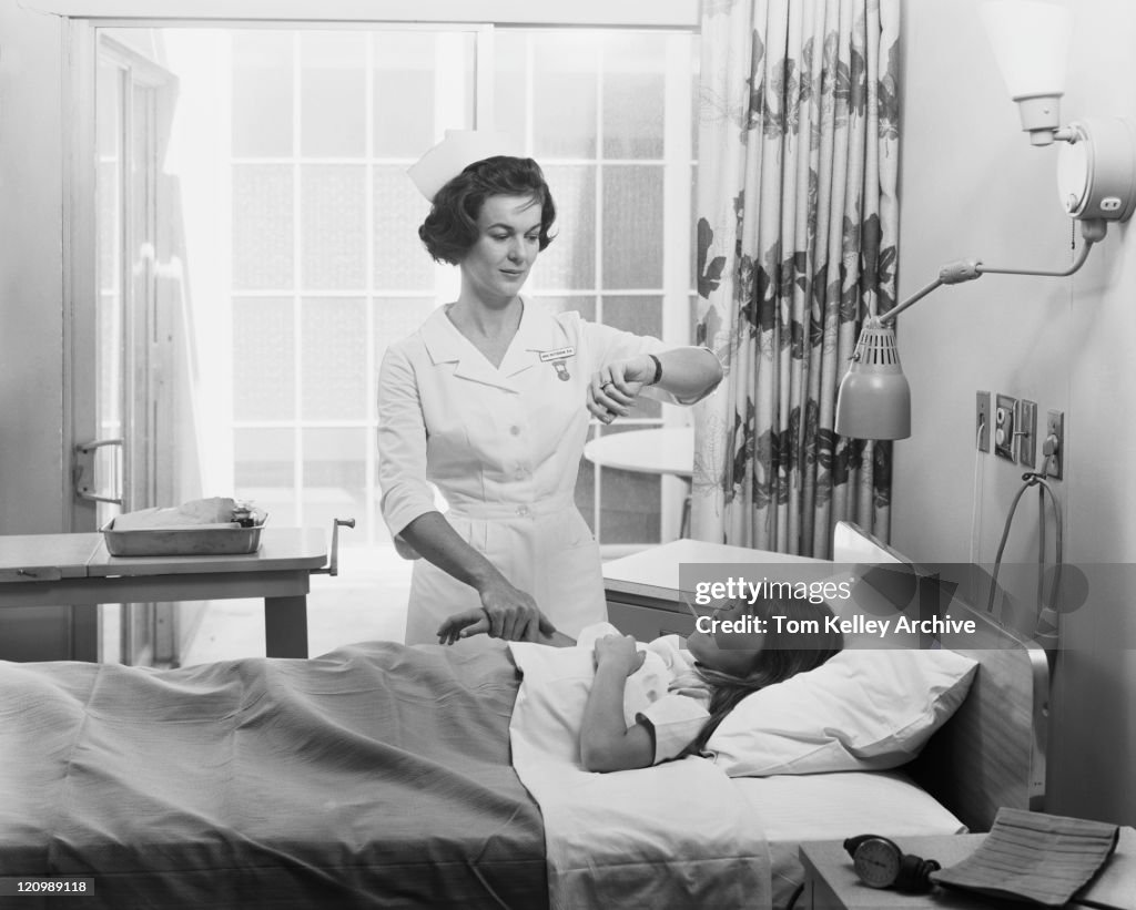 Nurse examining temperature and taking pulse of girl
