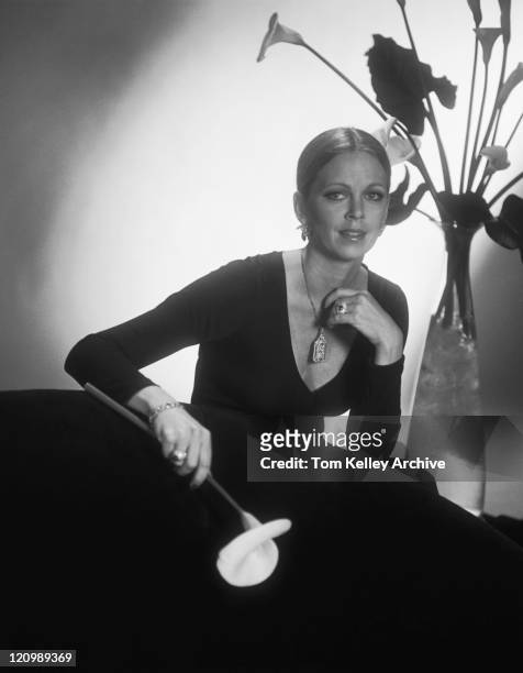 giovane donna seduta sul divano e tenendo fiori, verticale - anno 1980 foto e immagini stock