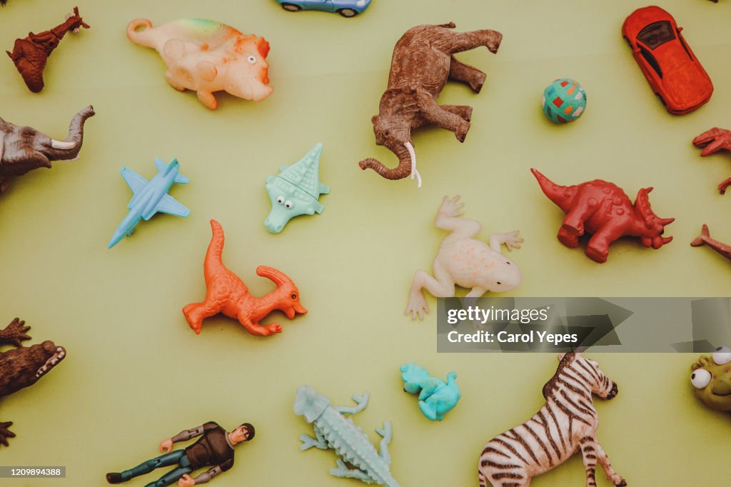 Collection of plastic and rubber toys on yellow surface.Top view.