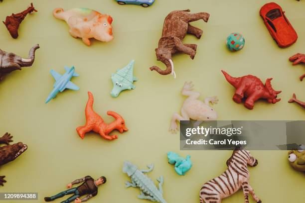 collection of plastic and rubber toys on yellow surface.top view. - extinct species stock pictures, royalty-free photos & images