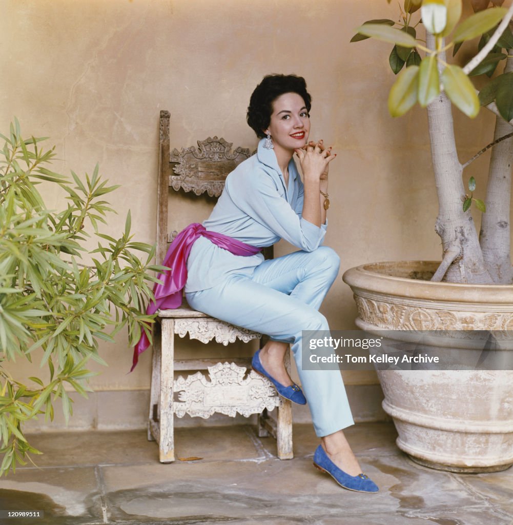 Mujer joven sentada en una silla, sonriendo, retrato