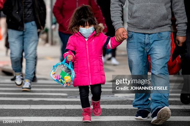 Girl, wearing a mask, walks down a street in the Corona neighborhood of Queens on April 14, 2020 in New York City. - New York will start making tens...