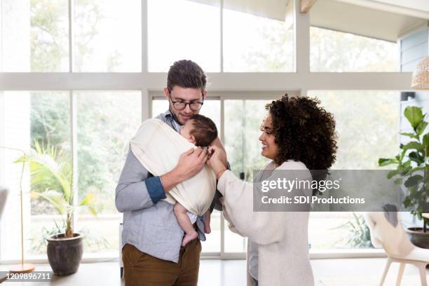 young father holds baby in infant sling - baby carrier stock pictures, royalty-free photos & images