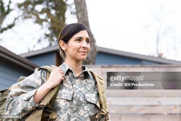 portrait of female soldier carrying gear - armed forces stock pictures, royalty-free photos & images