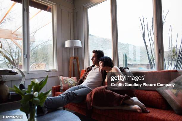 inhalt junges paar sitzt zu hause und schaut auf den regen - window rain stock-fotos und bilder