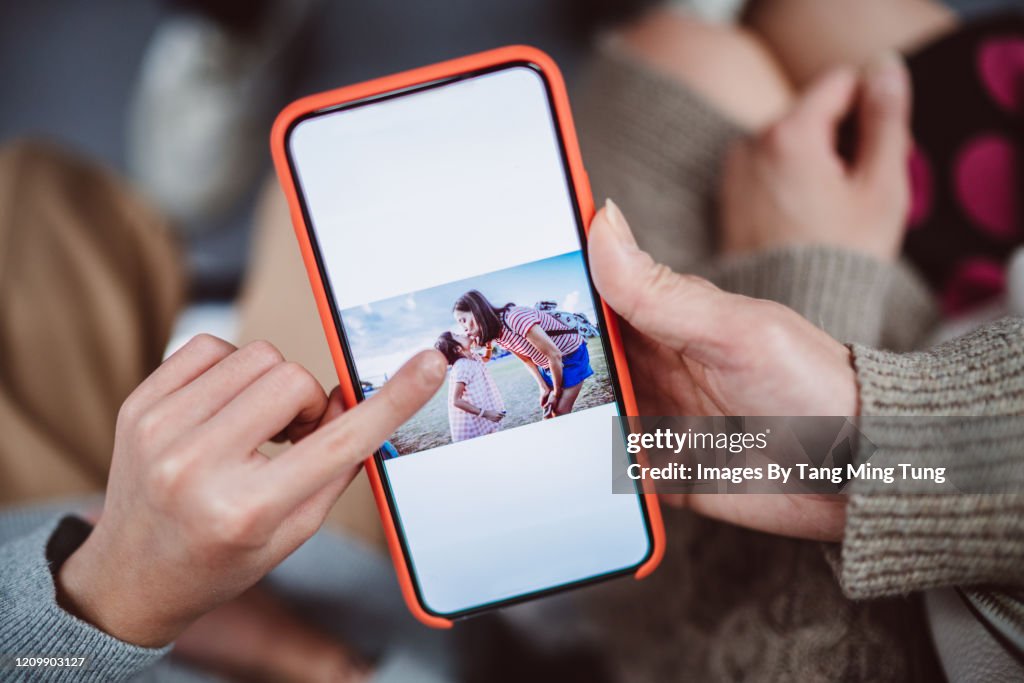Close-up of mom & daughter’s hands using smartphone together