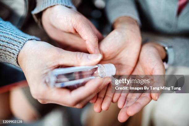 mom squeezing hand sanitizer onto her littler daughter’s hands - hand sanitizer stock-fotos und bilder