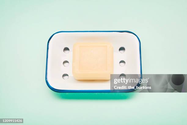 still life of an enamel soap dish and soap for washing hands on turquoise colored background - saboneteira imagens e fotografias de stock