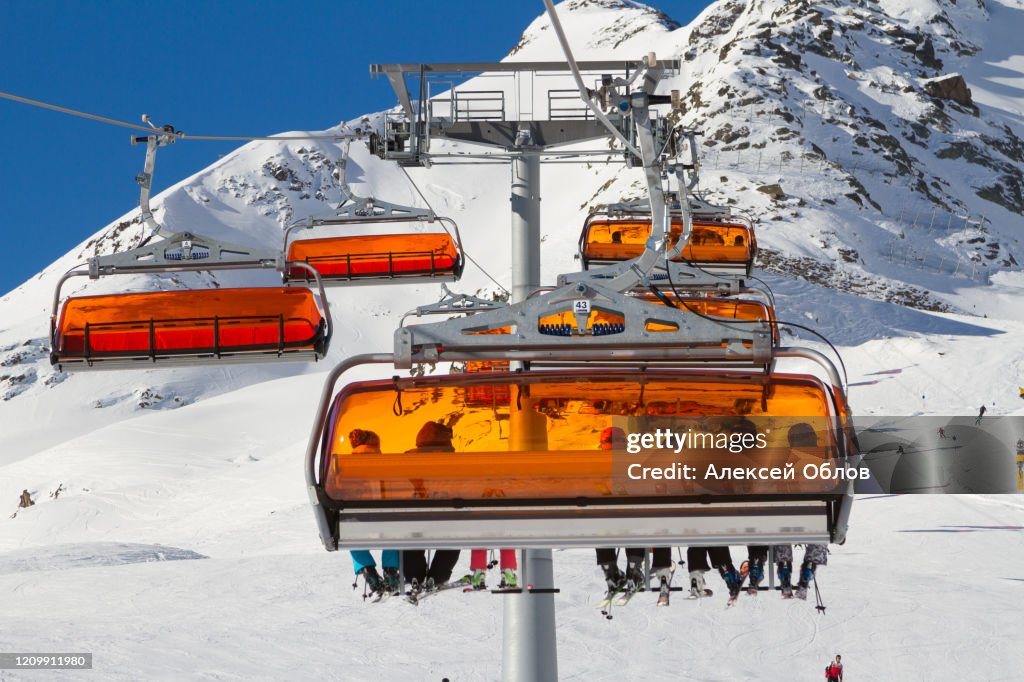 Panorama of ski resort in Soelden, Tirol, Austria. Bright orange ski carriage and skiers. Alps mountains.