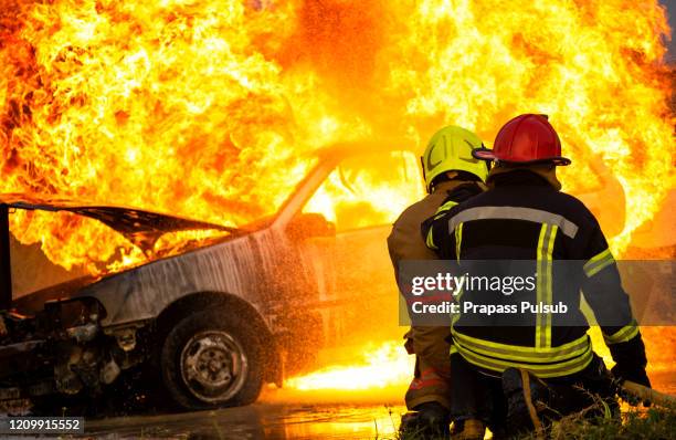 fireman using water and extinguisher car is on fire,firefighter using extinguisher and water from hose for fire fighting,burning car gas - carro de bombeiro fotografías e imágenes de stock