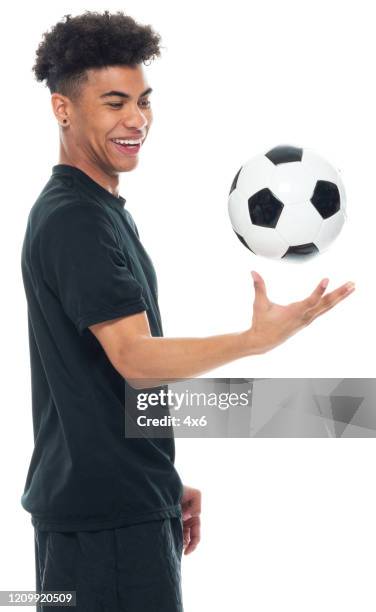 afrikaanse etniciteit jonge mannelijke voetballer die zich voor witte achtergrond bevindt die sportenkleding draagt en voetbalbal houdt en voetbal speelt - sport en het gebruiken van sportenbal - boy holding picture cut out stockfoto's en -beelden