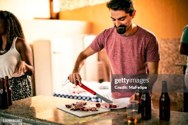 schöne hipster kerl serviert grillwürste in einer grillparty - bierwurst stock-fotos und bilder