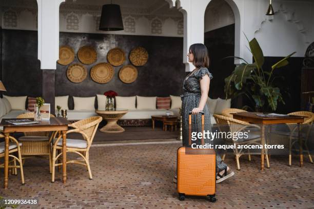 side view of young woman with an orange suitcase in the hotel - morocco interior ストックフォトと画像