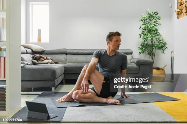 man practising yoga at home - strekken stockfoto's en -beelden