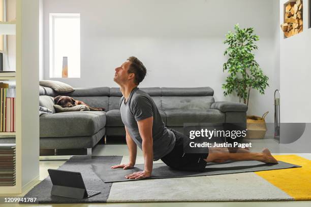 man practising yoga at home - man middelbare leeftijd woonkamer stockfoto's en -beelden