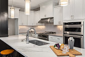 beautiful kitchen in new luxury home with island, pendant lights, and hardwood floors.