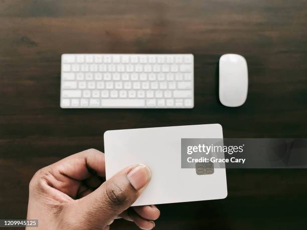 woman holds credit card to make online purchase - hand holding credit card stock pictures, royalty-free photos & images