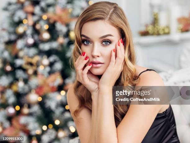 young beautiful woman standing next to the christmas tree - beautiful woman christmas stock pictures, royalty-free photos & images