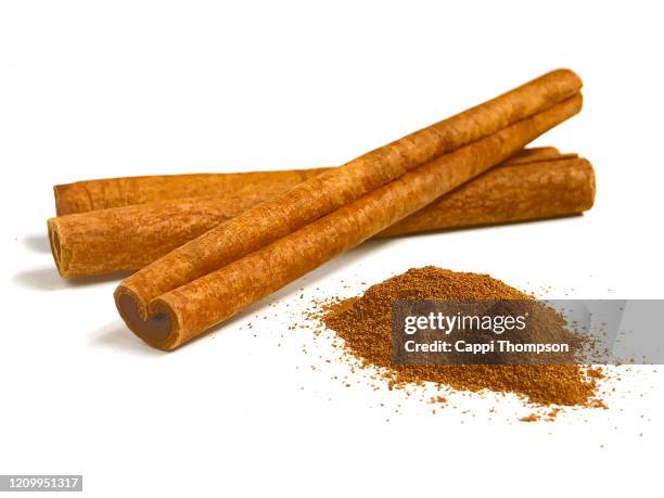 cinnamon sticks and ground cinnamon over white background - zimt stock-fotos und bilder