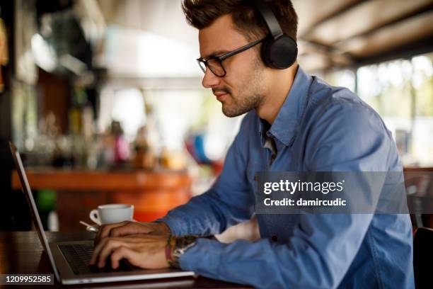 junger mann mit laptop in der cafeteria - mann headset stock-fotos und bilder