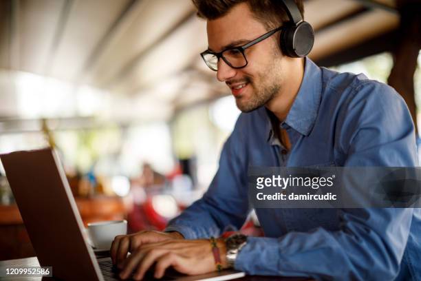 young man using laptop in cafeteria - remote location stock pictures, royalty-free photos & images