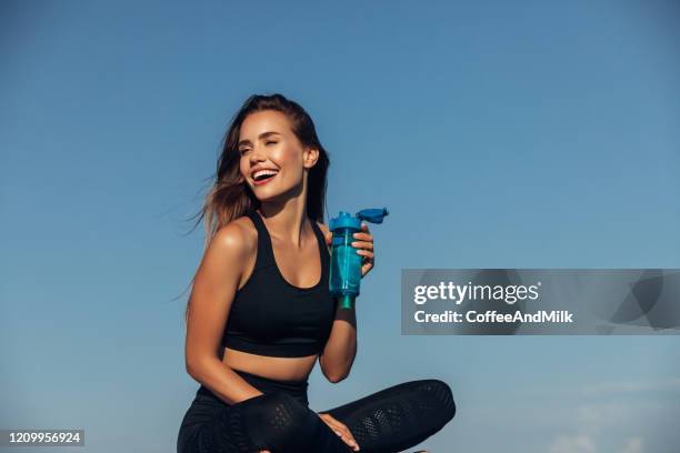 mujer fitness bebe agua frente al fondo marino - chica bebiendo agua fotografías e imágenes de stock