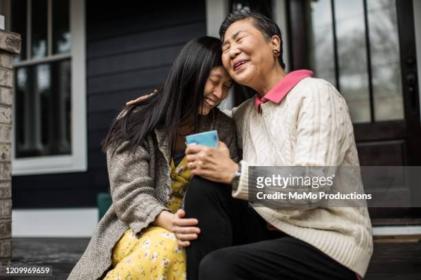 adult woman and senior mother talking on front porch - asian discuss photos et images de collection