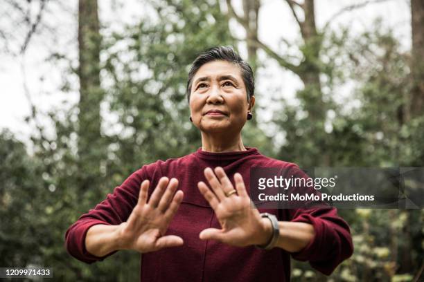 senior woman doing tai chi outdoors - tai chi imagens e fotografias de stock