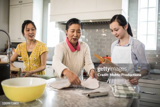 grandmother, granddaughter and mother cooking in kitchen - generationsunterschied stock-fotos und bilder