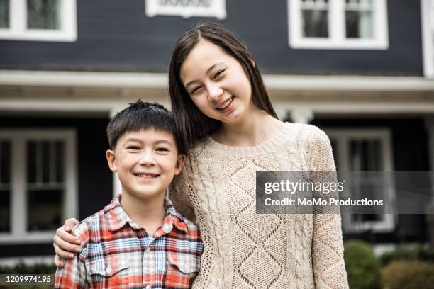 portrait of brother and sister in front of house - brothers boys cuddle stock pictures, royalty-free photos & images