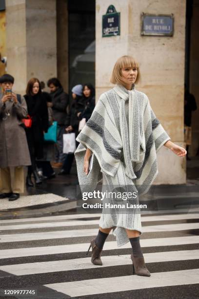 Guest wearing poncho knit jumper and skirt outside Giambattista Valli during Paris Fashion Week Womenswear Fall/Winter 2020/2021 Day Eight on March...