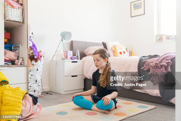 young girl meditating in her bedroom - child mental health wellness stock-fotos und bilder
