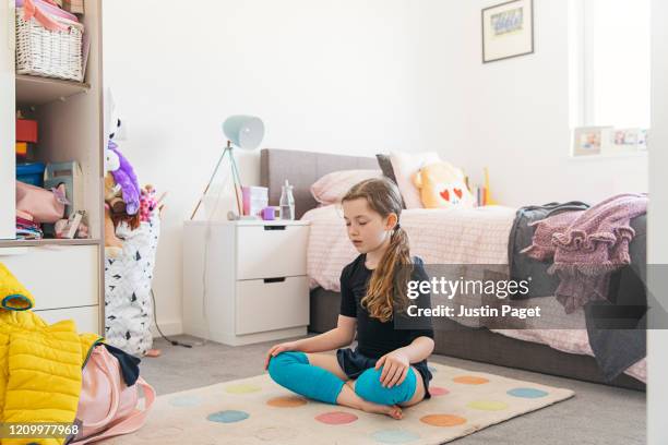 young girl meditating in her bedroom - child mental health wellness foto e immagini stock