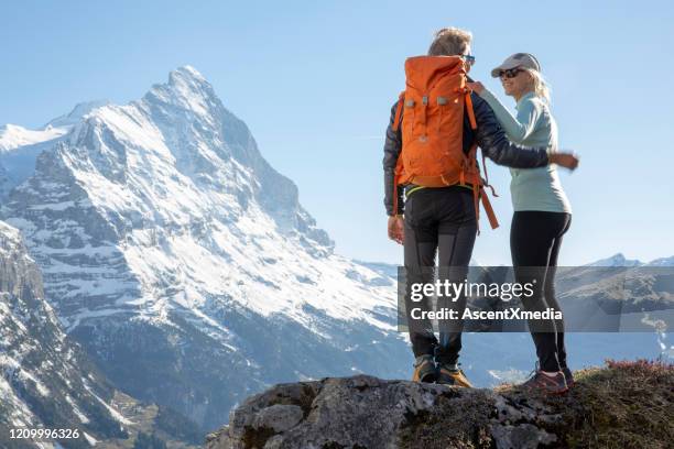 hiking couple ascend alpine slope, in mountains - grindelwald switzerland stock pictures, royalty-free photos & images