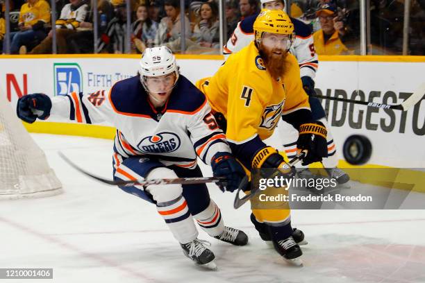 Ryan Ellis of the Nashville Predators flips a puck past Kailer Yamamoto of the Edmonton Oilers during the second period at Bridgestone Arena on March...