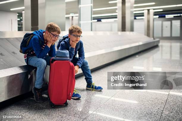 sad little boys at the airport waiting for the lost luggage - lost generation stock pictures, royalty-free photos & images