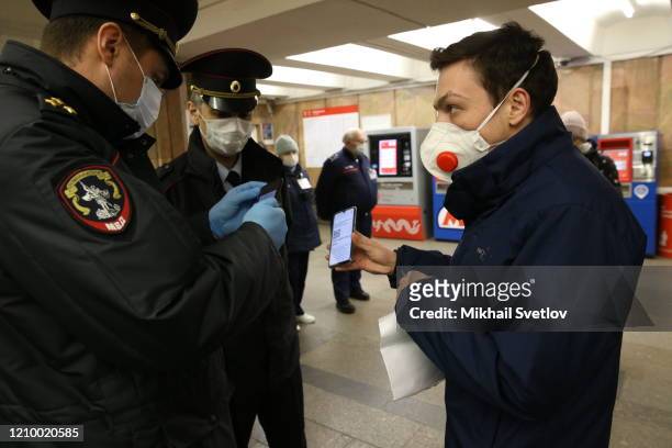 Police officer checks the ID with a QR-code and documents of a commuter at Moscow Metro Station on April 15, 2020 in Moscow, Russia. President...