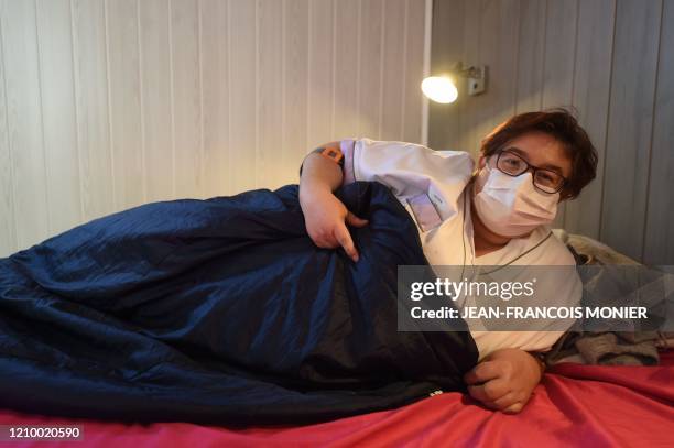 Sandrine Lalouze, 42 years old caregiver, mother of two daughters aged 12 and 16, smiles behind her protective mask as she poses in a bedroom of a...