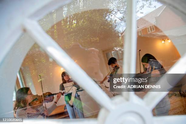 Ruth Jarman and her children, Helen, Sophie and Tom practice a string quartet arrangement of 'Somewhere over the Rainbow' in their music room in...