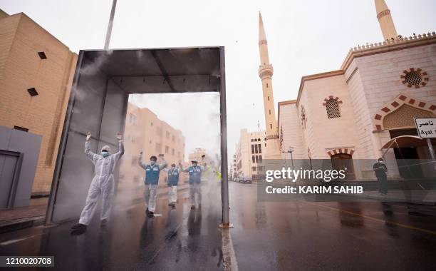 Health volunteers pass through a sterilisation chamber installed to disinfect residents entering and leaving the Naif area in the Gulf emirate of...