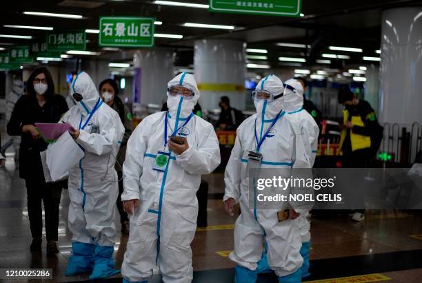 Transport personnel wearing hazmat suits wait for travellers arriving from Wuhan to guide them to buses, which will take them to their quarantine...