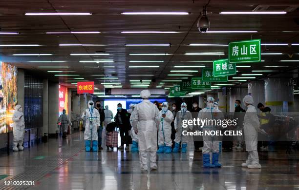 Transport personnel wearing hazmat suits wait for travellers arriving from Wuhan to guide them to buses, which will take them to their quarantine...