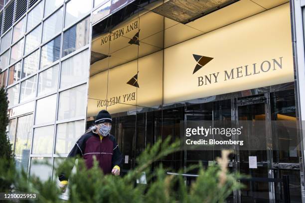 Pedestrian wearing a protective mask passes in front of a Bank of New York Mellon Corp. Office building in New York York, U.S., on Saturday, April...