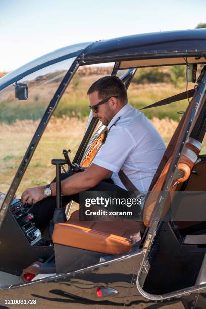 helicopter pilot adjusting navigational equipment - helicopter pilot stock pictures, royalty-free photos & images