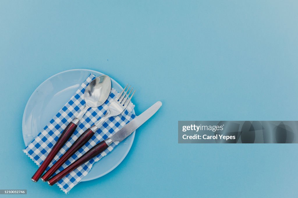 Table setting empty plate and cutlery in blue