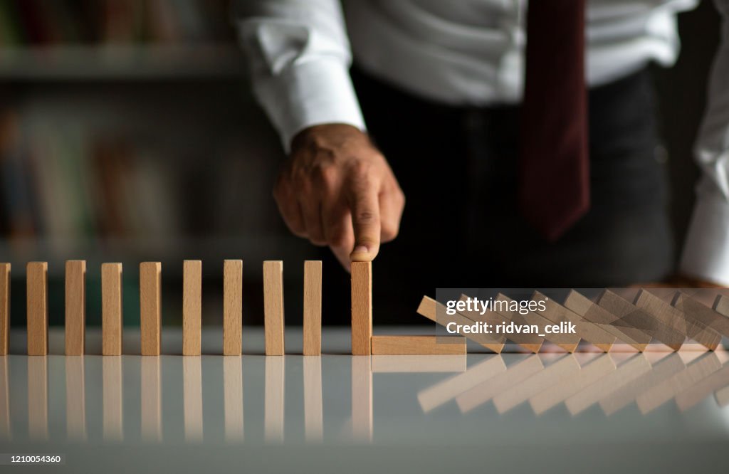 Geschäftsmann Stop Domino Effect. Risikomanagement und Versicherungskonzept