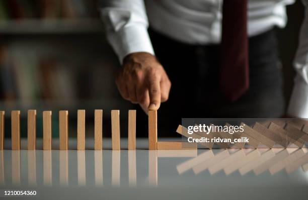 businessman stop domino effect. risk management and insurance concept - administration imagens e fotografias de stock