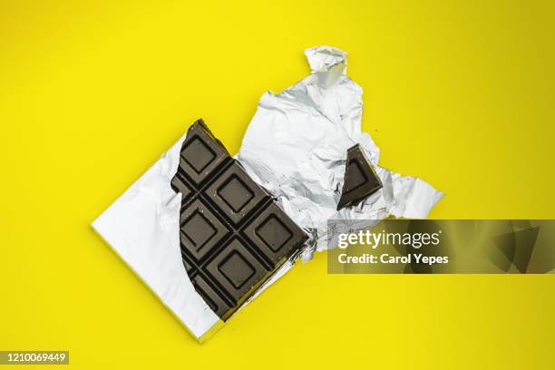 bitten chocolate bar in yellow background - cioccolato scuro foto e immagini stock