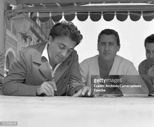 Italian director Federico Fellini portrayed while signing autographs with the italian actor Alberto Sordi, in Lido, Venice for presenting the movie...