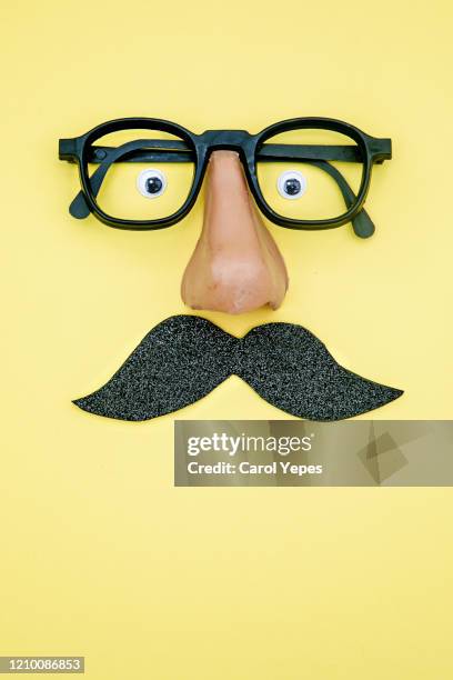 novelty glasses with fake moustache and googly eyes.yellow background - mustache isolated stockfoto's en -beelden